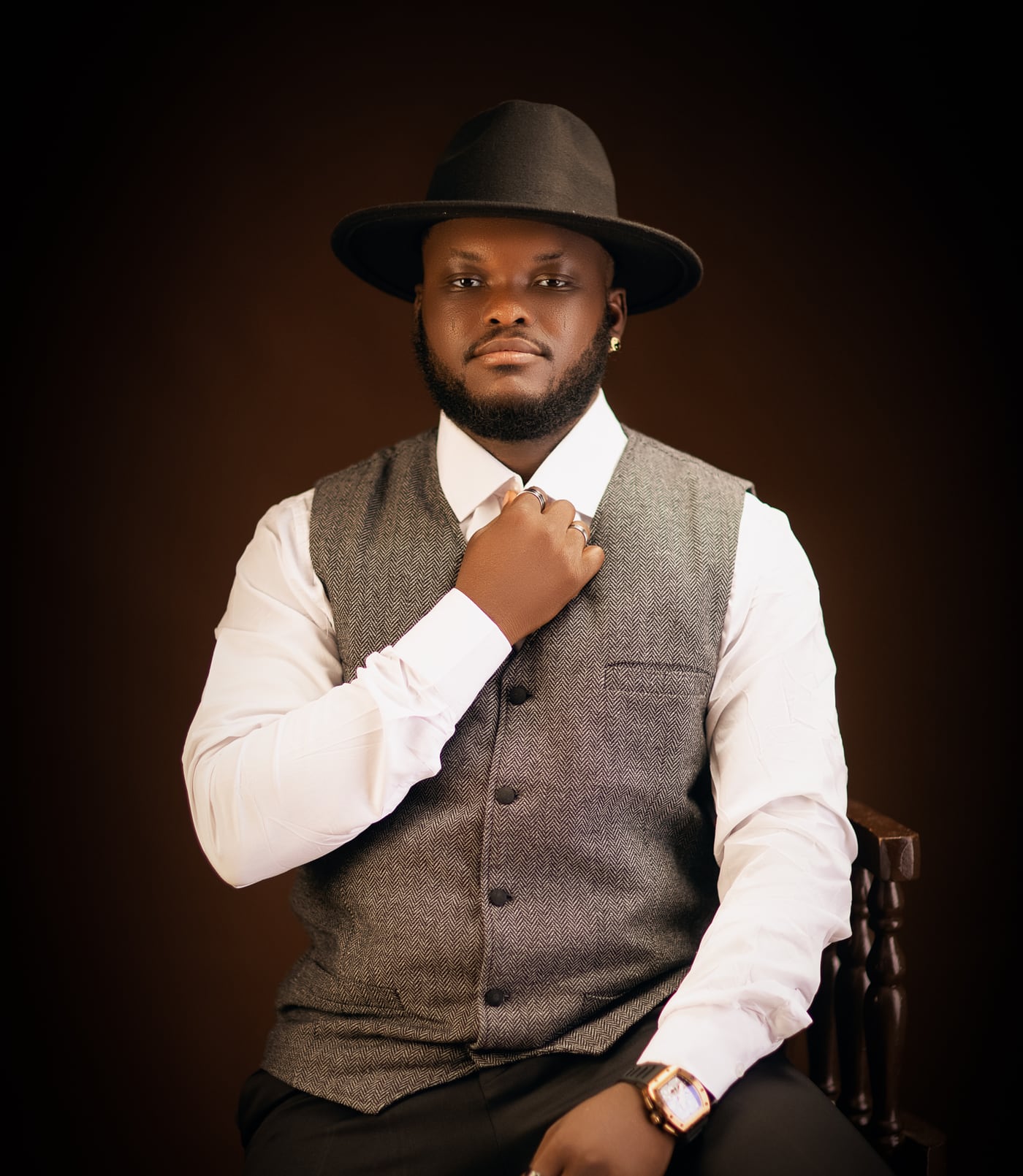 Ayoola Abiola, founder of AzillionNet, seated in a grey waistcoat and black fedora